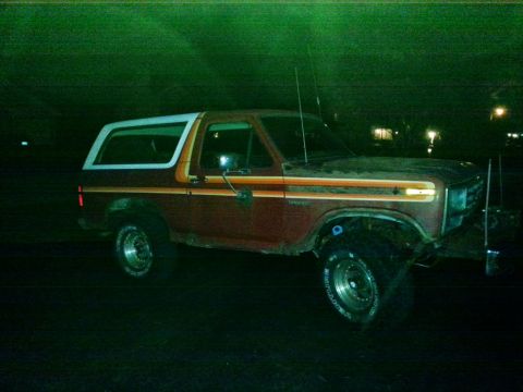 1984 Ford Bronco - Nighttime photograph of a red Ford Bronco in profile, not a document.