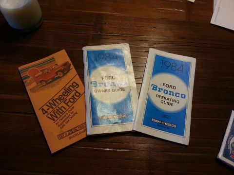 1984 Ford Bronco - Sales/owner literature: a Ford '4-Wheeling With Ford' booklet beside 1984 Ford Bronco Owner Guide and Operating Guide covers.