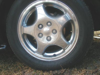 1997 Ford Taurus - Close-up of a chrome wheel with a five-spoke design and five visible lug nuts.