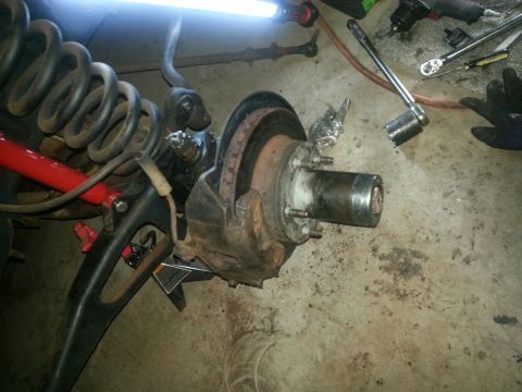 1984 Ford Bronco - Photograph of a vehicle front suspension, coil spring, brake rotor and exposed spindle during repair, not a document.