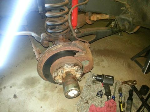 1984 Ford Bronco - Photograph of a brake rotor and grease-packed wheel hub with an impact wrench during a brake job, not a document.