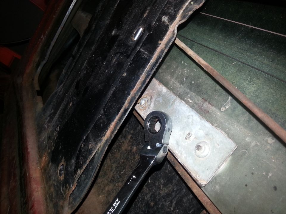 Photo of a ratchet wrench on a body mount bracket inside a vehicle floor