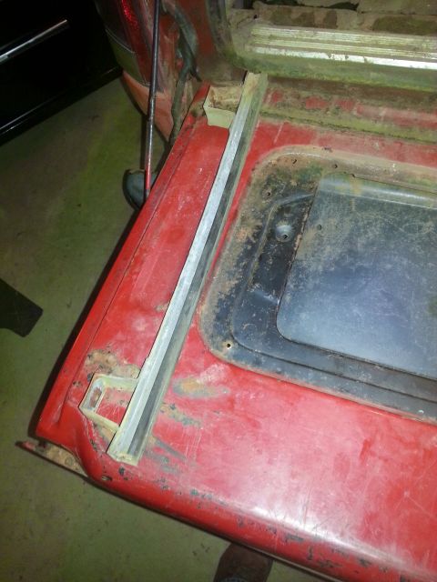 1984 Ford Bronco - Photo of a red vehicle's window opening and metal trim during disassembly, not a document.