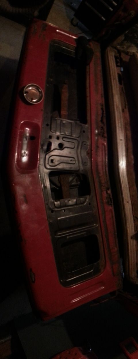 1984 Ford Bronco - Photo of a stripped red tailgate panel with inner bracing, not a technical document.