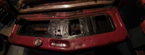 1984 Ford Bronco - Photo of a red vehicle tailgate showing its inner structure, not a document.