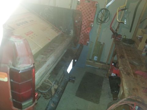 1984 Ford Bronco - Photo of a red vehicle body on a stand in a garage during restoration, not a document.