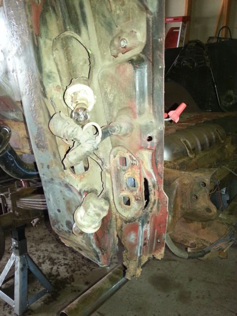 1984 Ford Bronco - Photograph of a corroded body panel resting on jack stands in a garage, not a document.