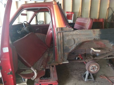 1984 Ford Bronco - Photograph of a partially disassembled red pickup truck in a garage, not a document.