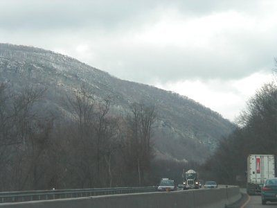1997 Ford Taurus - A view from a highway shows a semi-trailer truck and other vehicles traveling on a cloudy day with a wooded mountain in the background.
