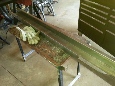 1984 Ford Bronco - Photograph of steel channel and work gloves on a bench in a shop, not a document.