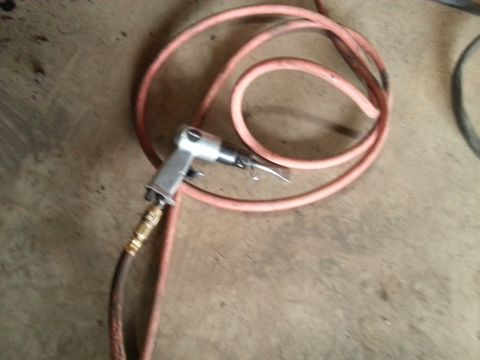 1984 Ford Bronco - Photograph of a pneumatic blow gun and coiled air hose on a garage floor, not a document.
