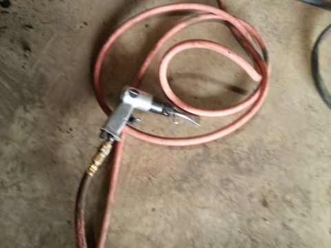 1984 Ford Bronco - Photograph of a pneumatic blow gun attached to a coiled red air hose lying on a garage floor.