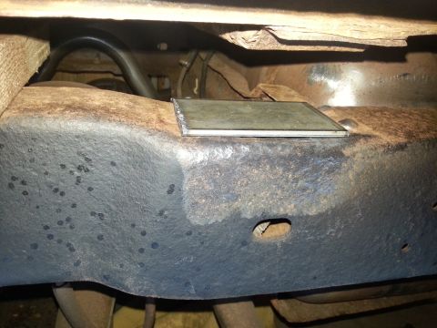 1984 Ford Bronco - Close-up view of a vehicle's underbody chassis, showing a metal plate affixed to the frame.