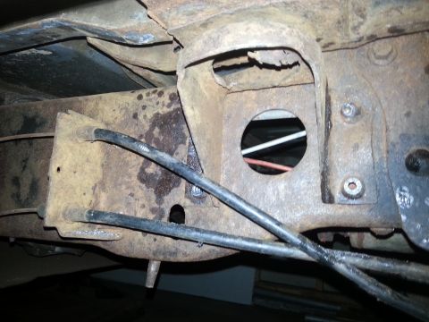 1984 Ford Bronco - Close-up of heavily rusted vehicle frame components and brake lines.