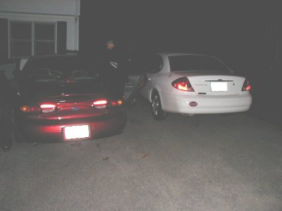 1997 Ford Taurus - Two sedans are parked outside a house at night, viewed from the rear.