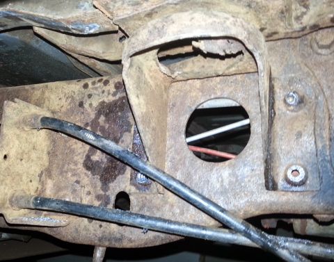 1984 Ford Bronco - The underside of a vehicle shows significant rust and wear on its frame components.