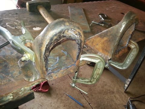 1984 Ford Bronco - Metal part being welded on a workbench, with tools including a sledgehammer and clamps.