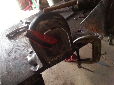1984 Ford Bronco - A metal part is being worked on with clamps and tools on a workbench.