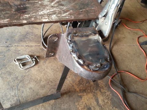 1984 Ford Bronco - A metal bracket is being welded, with clamps and electrical cords visible on the floor.