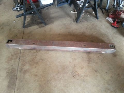 1984 Ford Bronco - A metal bumper part is shown on a concrete floor in a garage setting.