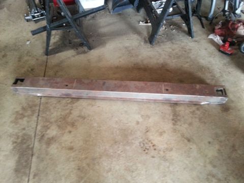 1984 Ford Bronco - A steel bumper, likely for a truck or SUV, lies on a concrete floor.