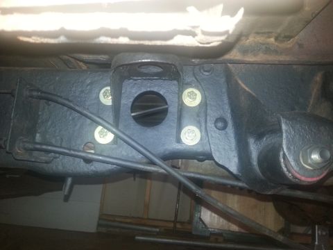 1984 Ford Bronco - Underside view of a vehicle's rear axle suspension bracket, showing mounting hardware and brake line.