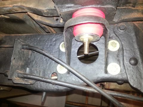 1984 Ford Bronco - Close-up view of a red polyurethane body mount bushing attached to a vehicle's frame.