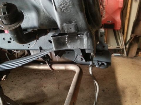 1984 Ford Bronco - Photograph of a freshly painted truck frame section with leaf spring and exhaust pipe in a shop.