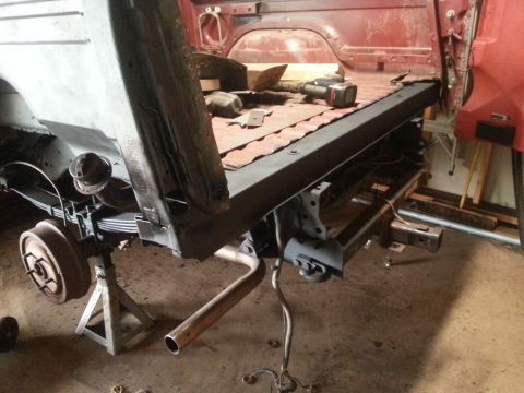 1984 Ford Bronco - Photograph of a pickup bed and rear frame with brake drum, leaf spring and exhaust during a rebuild.