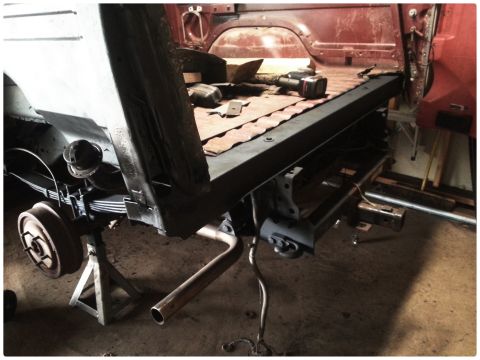 1984 Ford Bronco - Photograph of a pickup bed and rear frame with brake drum, leaf spring and exhaust during a rebuild.