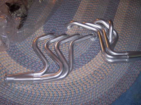 1990 Ford Bronco - Exhaust headers are displayed on a carpeted surface, with a cat visible in the upper left corner.