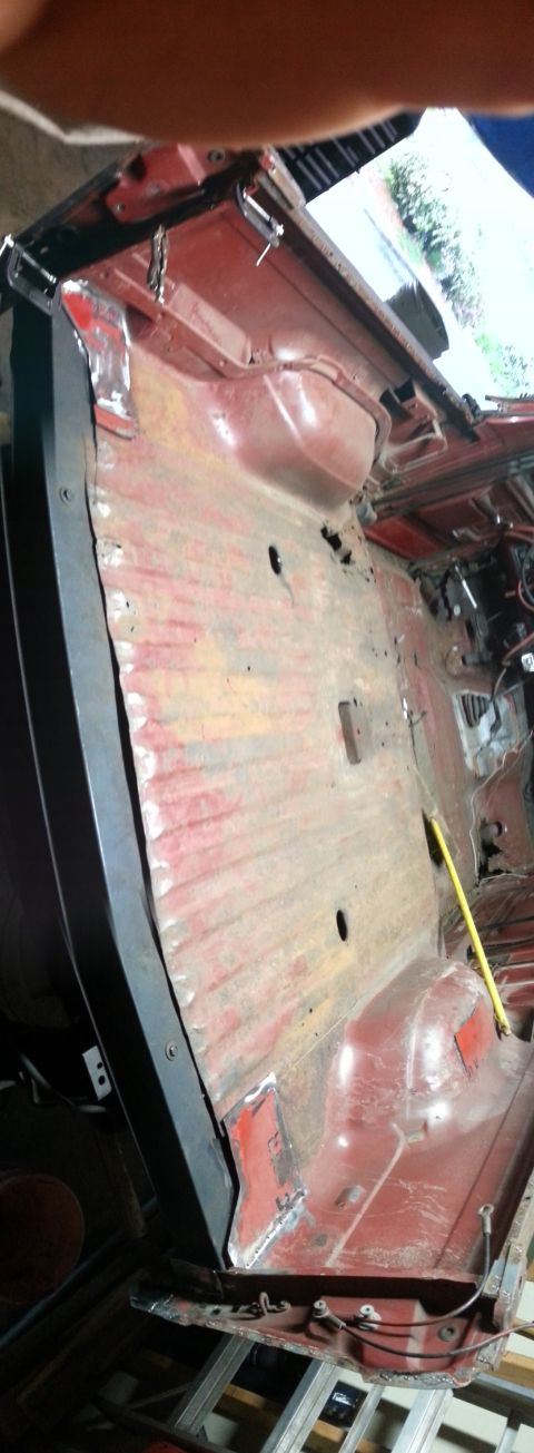 1984 Ford Bronco - Workshop photo of a stripped red cab floor pan, not a technical document.