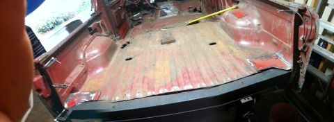 1984 Ford Bronco - Workshop photo of a stripped red cab floor pan, not a technical document.
