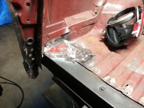 1984 Ford Bronco - Workshop close-up of a welded sheet-metal floor patch on a red body, not a technical document.