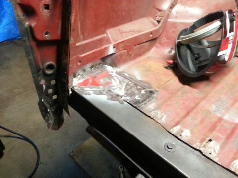 1984 Ford Bronco - Workshop close-up of a welded sheet-metal floor patch on a red body, not a technical document.