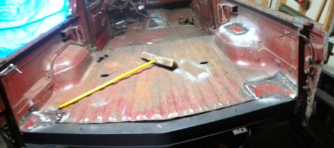 1984 Ford Bronco - Workshop photo of a red cab floor pan with a measuring stick laid across it, not a technical document.