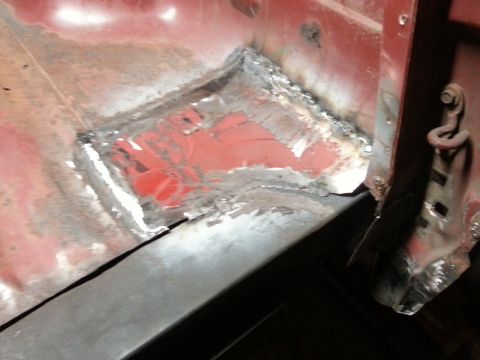 1984 Ford Bronco - Workshop close-up of a fresh welded floor patch beside a body mount, not a technical document.