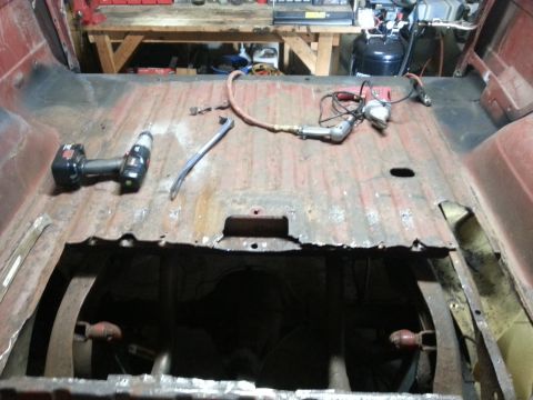 1984 Ford Bronco - Photo of a truck cab floor pan removed during restoration with power tools resting on the metal surface.