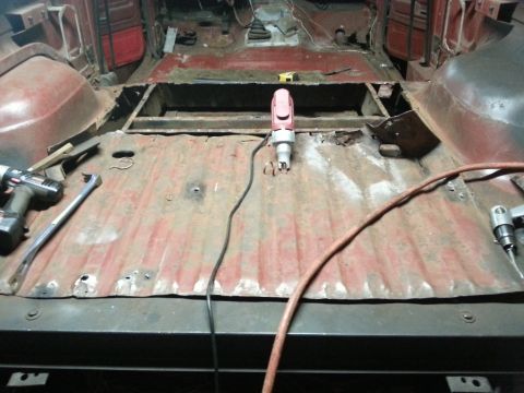 1984 Ford Bronco - Photo of a truck floor pan under restoration with an air tool and hose across the panel.