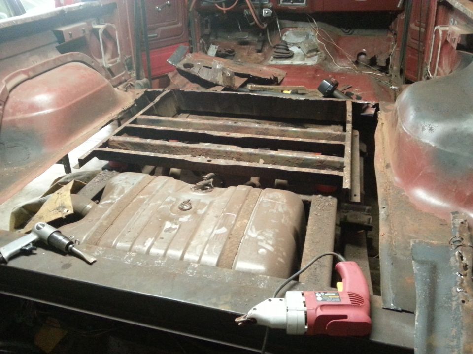 Truck floor removed exposing frame crossmembers and fuel tank below the cab