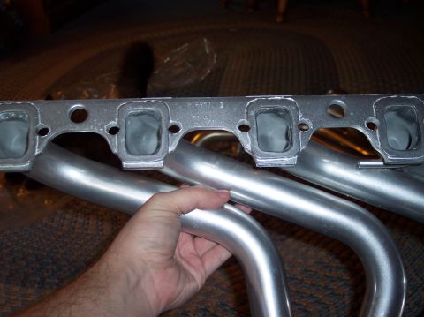 1990 Ford Bronco - Exhaust manifold part shown up close, with a hand holding one of the pipes.