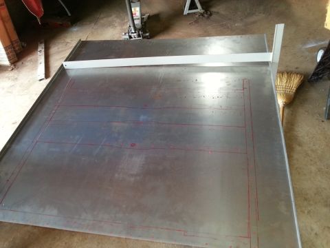 1984 Ford Bronco - Photo of a metal panel on a fabrication table marked with red layout lines during restoration.