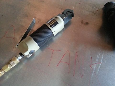 1984 Ford Bronco - Photo of an air flange tool on a metal panel labeled TANK in red marker during fabrication.