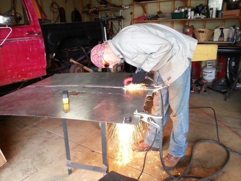 1984 Ford Bronco - Photo of a person cutting a metal panel on a table with sparks during fabrication.