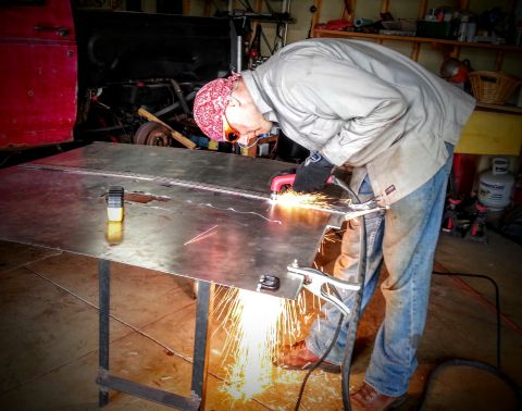 1984 Ford Bronco - Photo of a person cutting a metal panel with sparks flying during a restoration project.