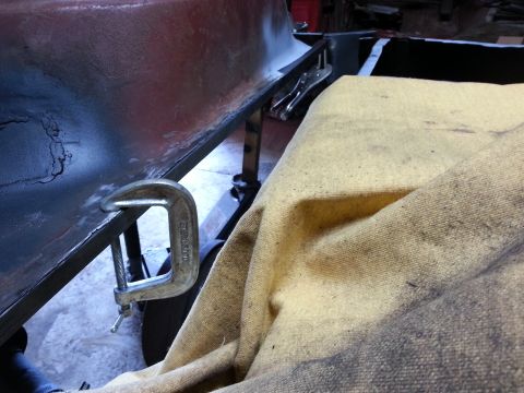 1984 Ford Bronco - Restoration work photo showing a clamped sheet-metal bed panel beside a moving blanket, not a technical document.