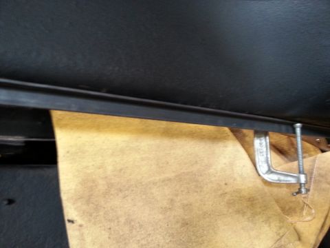 1984 Ford Bronco - Workshop photo of a clamped metal piece during a body restoration, not a technical document.