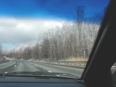1997 Ford Taurus - A view from inside a vehicle shows a highway passing by snow-covered trees under a bright blue sky.