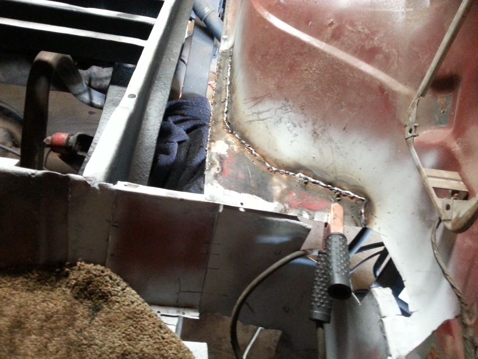 Photo of welded seams on a body panel with grinder handle visible