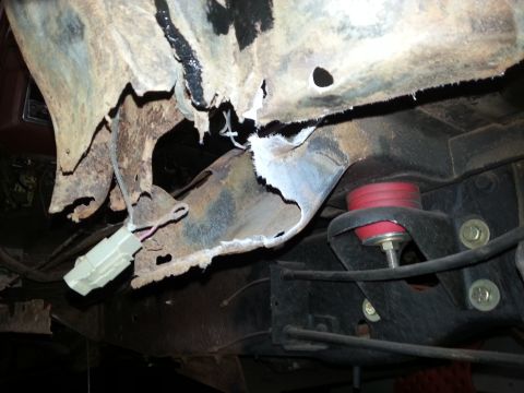 1984 Ford Bronco - Undercarriage photo of corroded body metal near a bump stop, not a technical document.